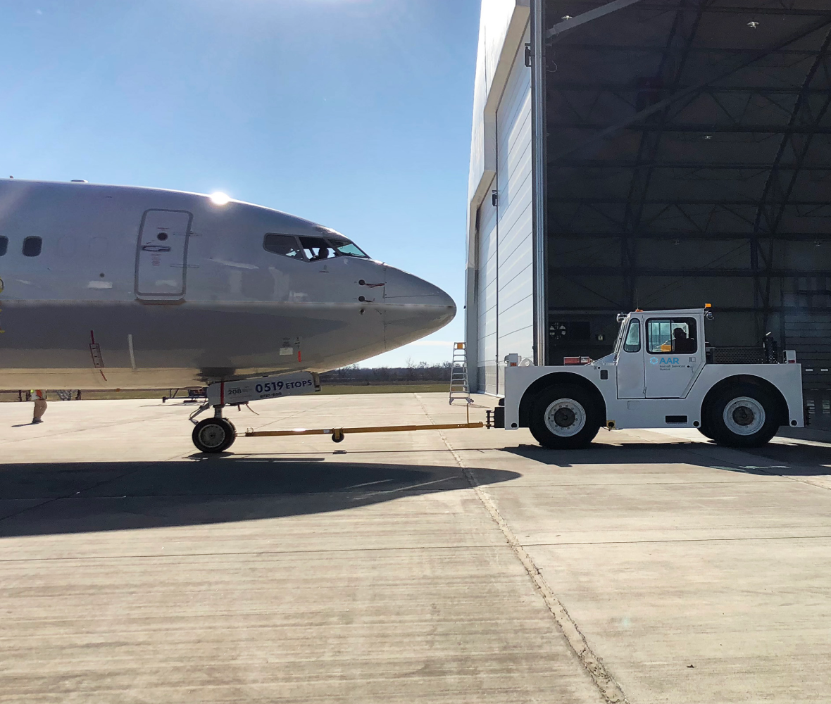 Truck pulling an airplane into a hangar