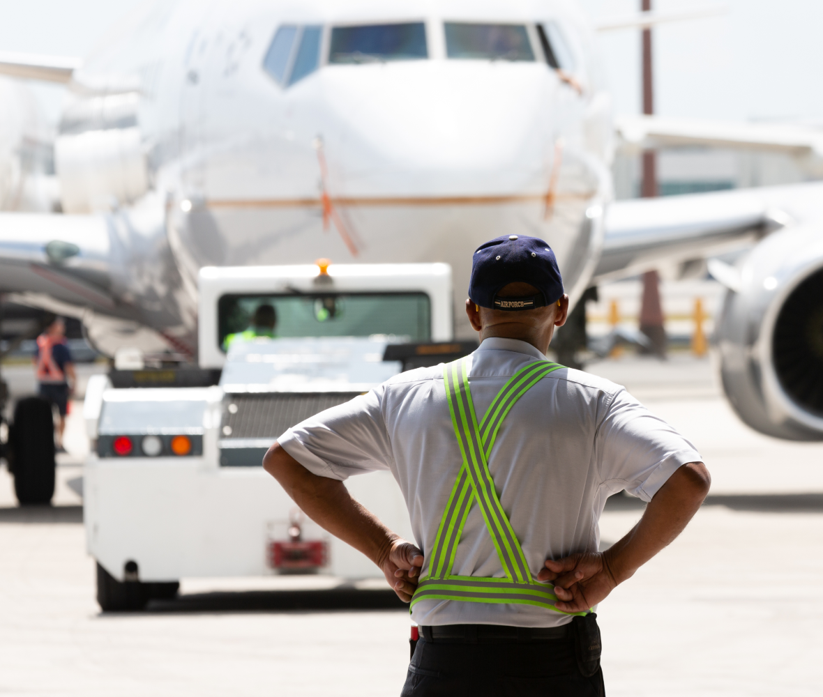 Person with arms on waist looking at an airplane