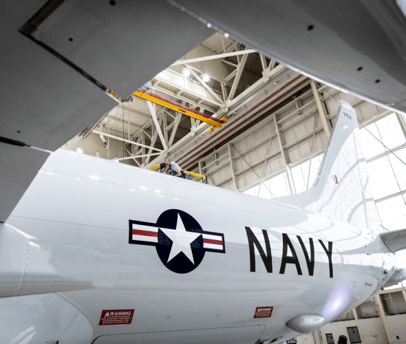 Mechanic on top of an airplane in a hanger